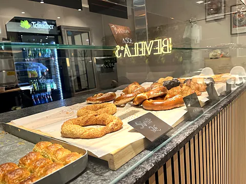 Simit und Gebäck auf der Theke, dahinter spiegelt sich der Neon-Schriftzug