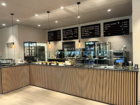 Theke mit Holzlamellen, Kuchenvitrine und Menütafeln an der Wand